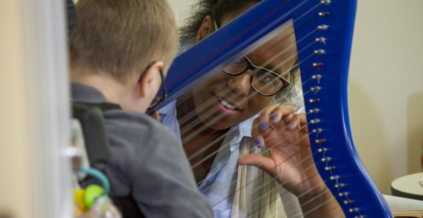 Woman looks through a small harp at a child