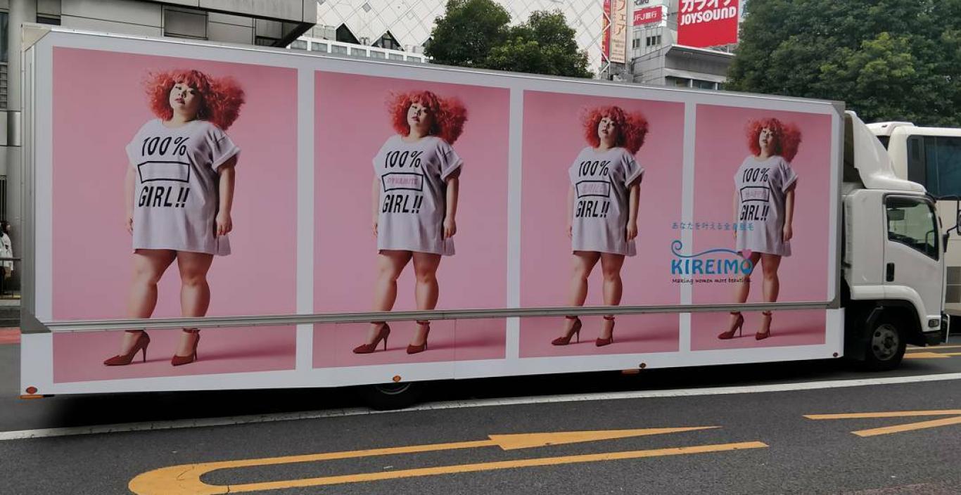 An advertisement on an 18-wheeler with a woman with red hair and a shirt that says 100% girl. Repeated four times on the truck.