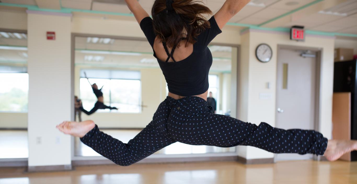 A dancer leaps in a Lesley dance studio.