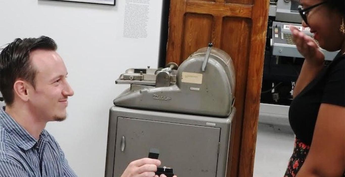 Man on one knee proposing with a jewelry box in hand