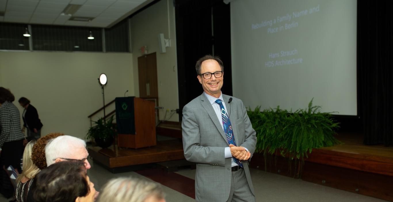 Hans Strauch in front of the audience, smiling, hands clasped