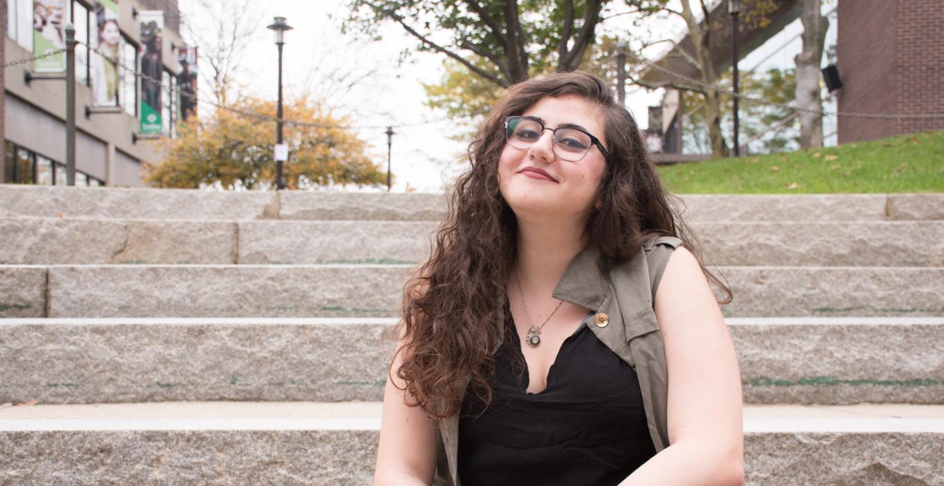 Jess Rizkallah sits on steps at Lesley University.
