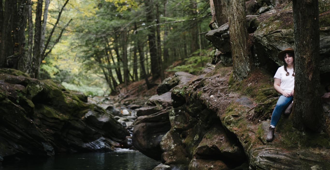 Photographer Kelly Burgess stands by a shady green Vermont swimming hole.