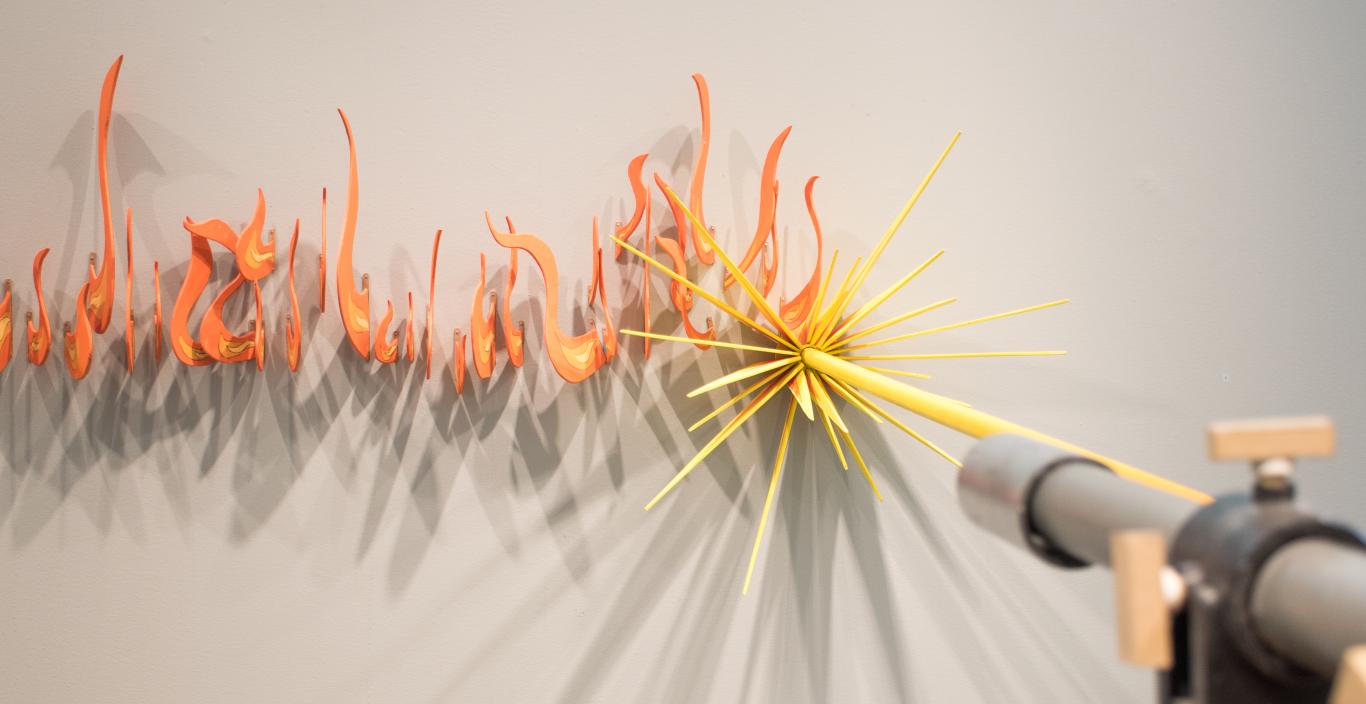 A sculpture of a laser cutter emits fire.