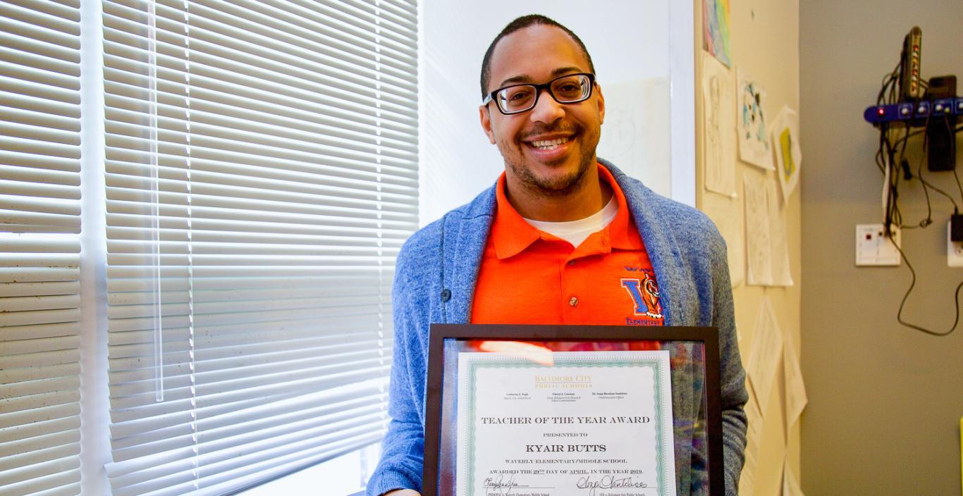 Kyair Butts holding his framed award.