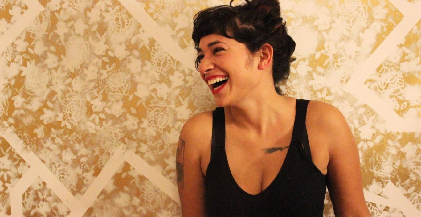 Melissa Lozada-Oliva laughing against a gold wall.