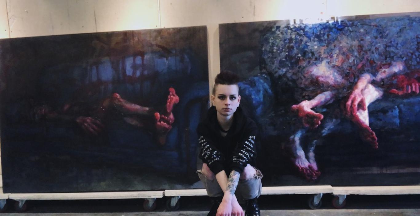 Moriah Faith in front of two of her paintings