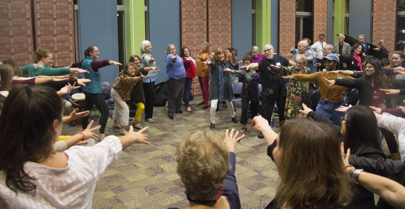 Dancers in a circle with their hands stretched out towards the middle of the circle. 