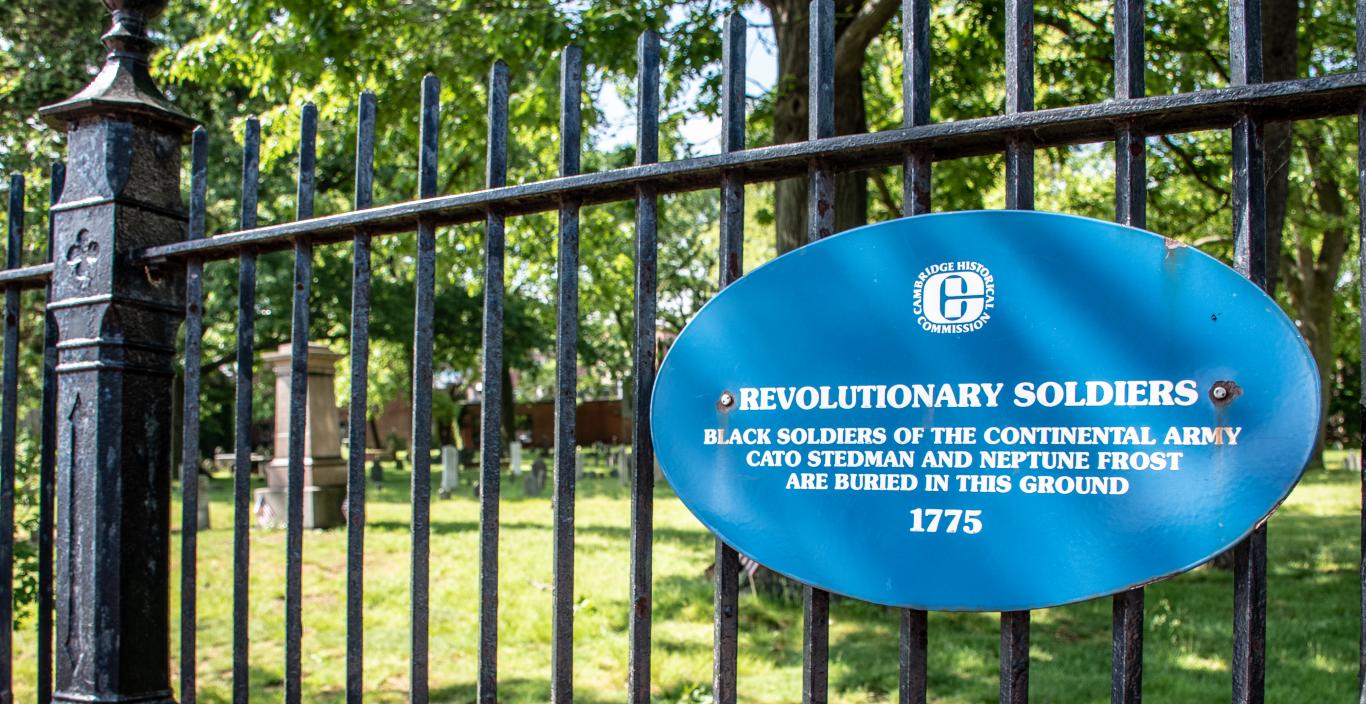 A sign on the cemetery's iron gate reads: Revolutionary Soldiers. Black soldiers of the Continental Army Cato Stedman and Neptune Frost are buried in this ground 1775. 