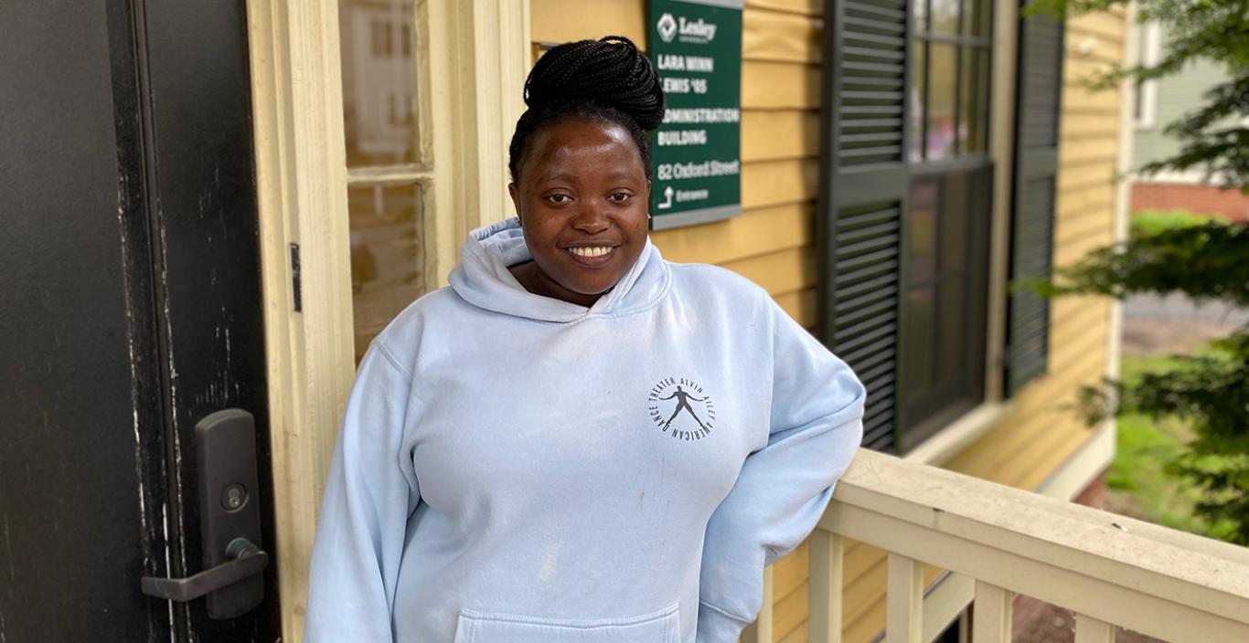 Redempta "Demi" Muhorakeye pictured in front of the yellow 82 Oxford St building on the Lesley campus.