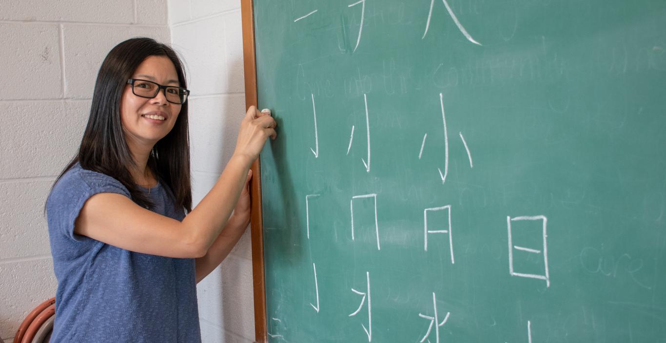 Ruiming Huang teaches Chinese characters at a blackboard