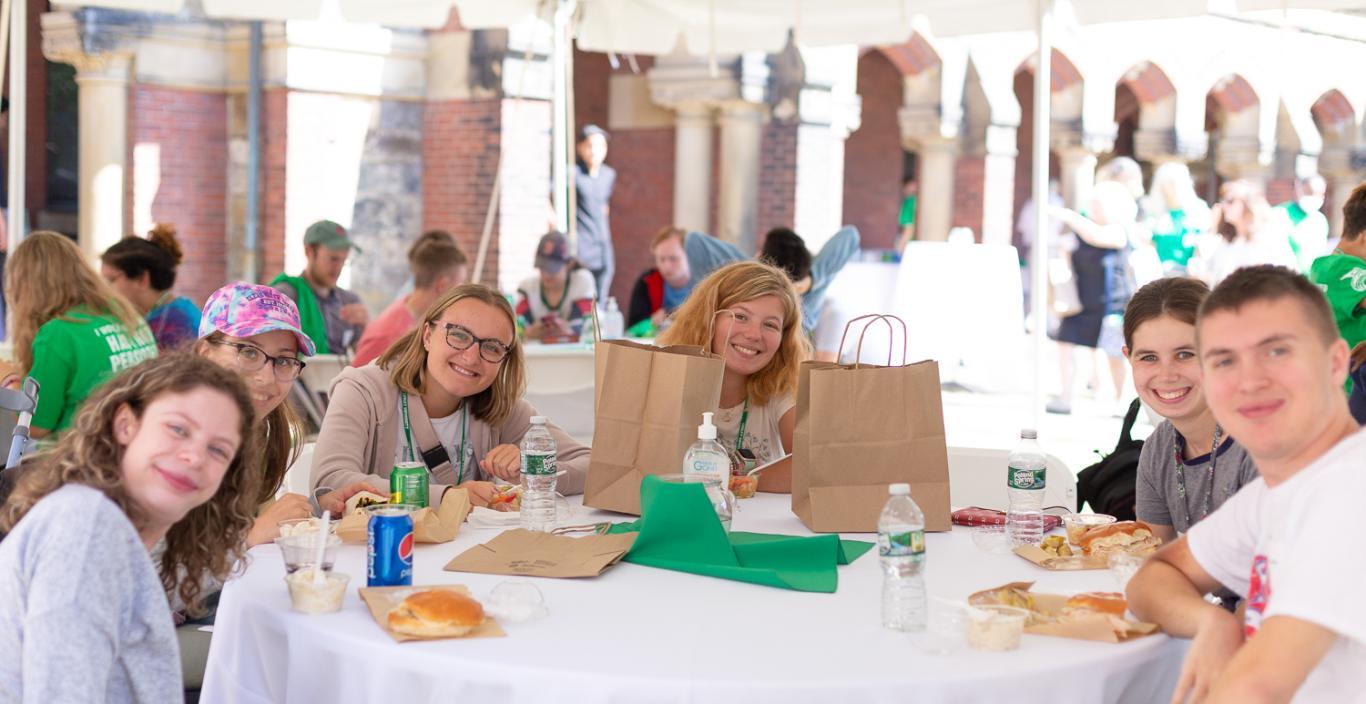 Students smile - sitting around a table outside at convocation