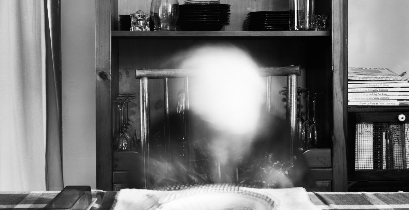 Black and white photo of someone at a dinner table who has been ghosted out