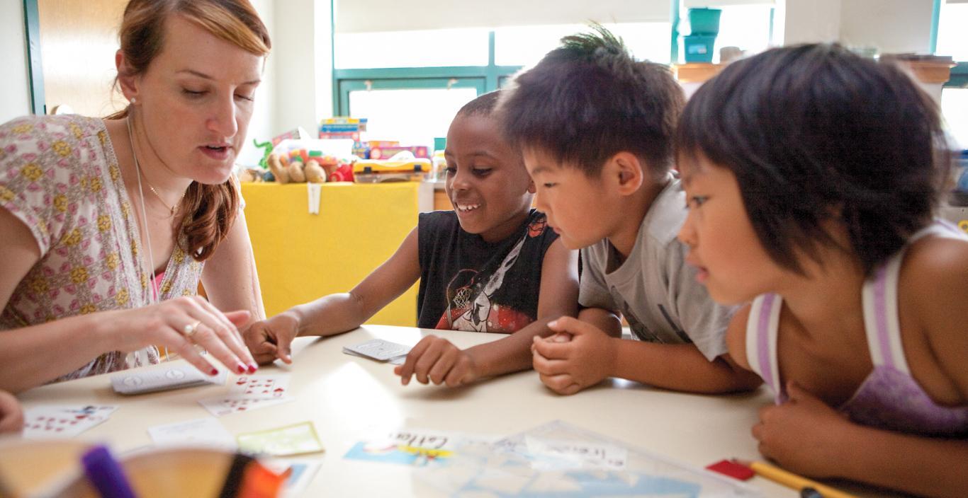 children playing cards and learning from their teacher