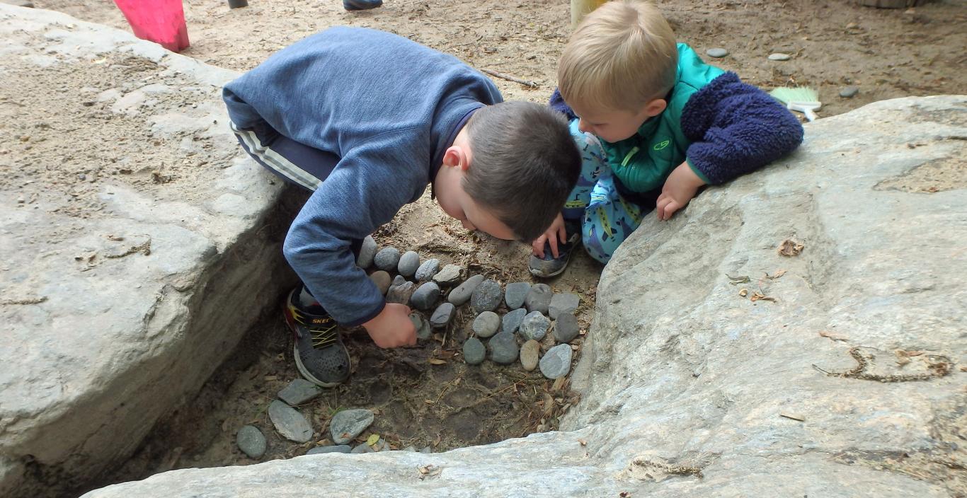 Two small children exploring rocks and sand
