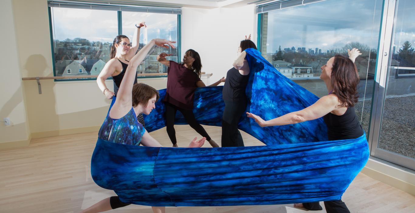 Dancers as part of a movement therapy class in a studio dancing with fabric.