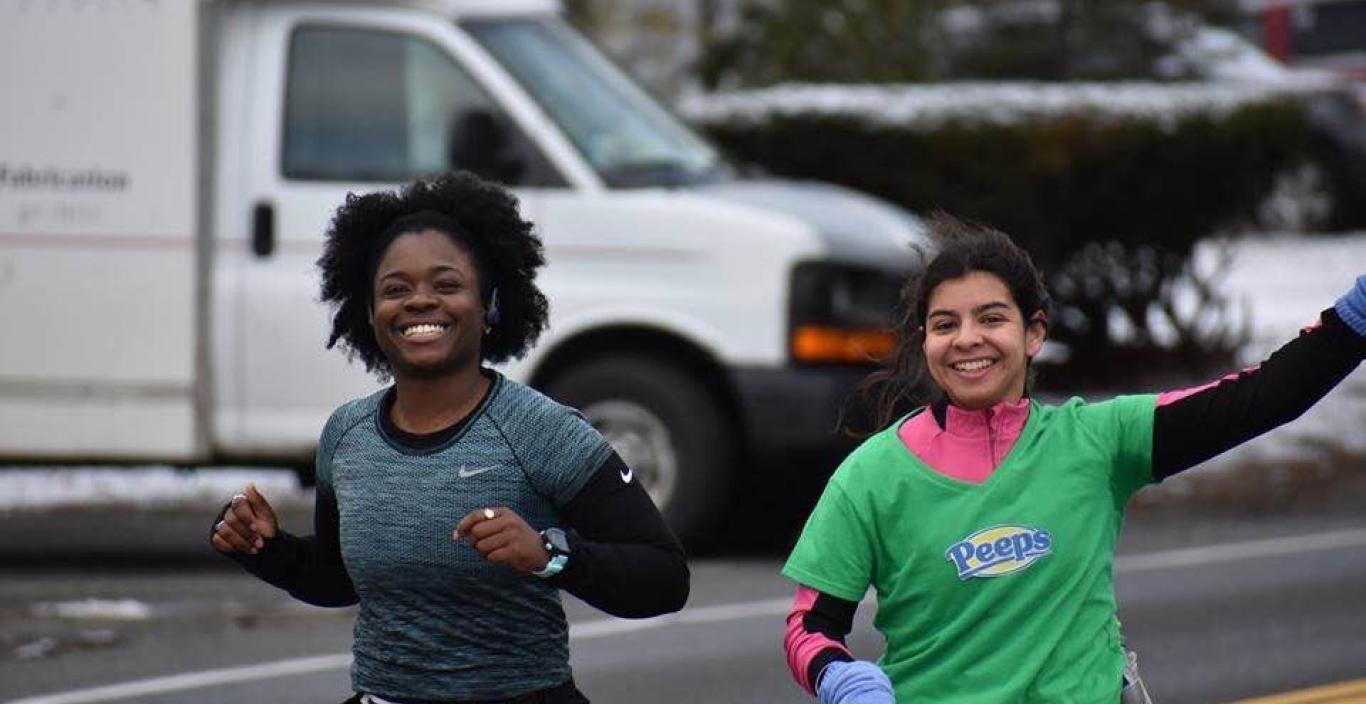 Imani Graham and Hanna Adams (who is on the right) smile and Hannah waves during a run.