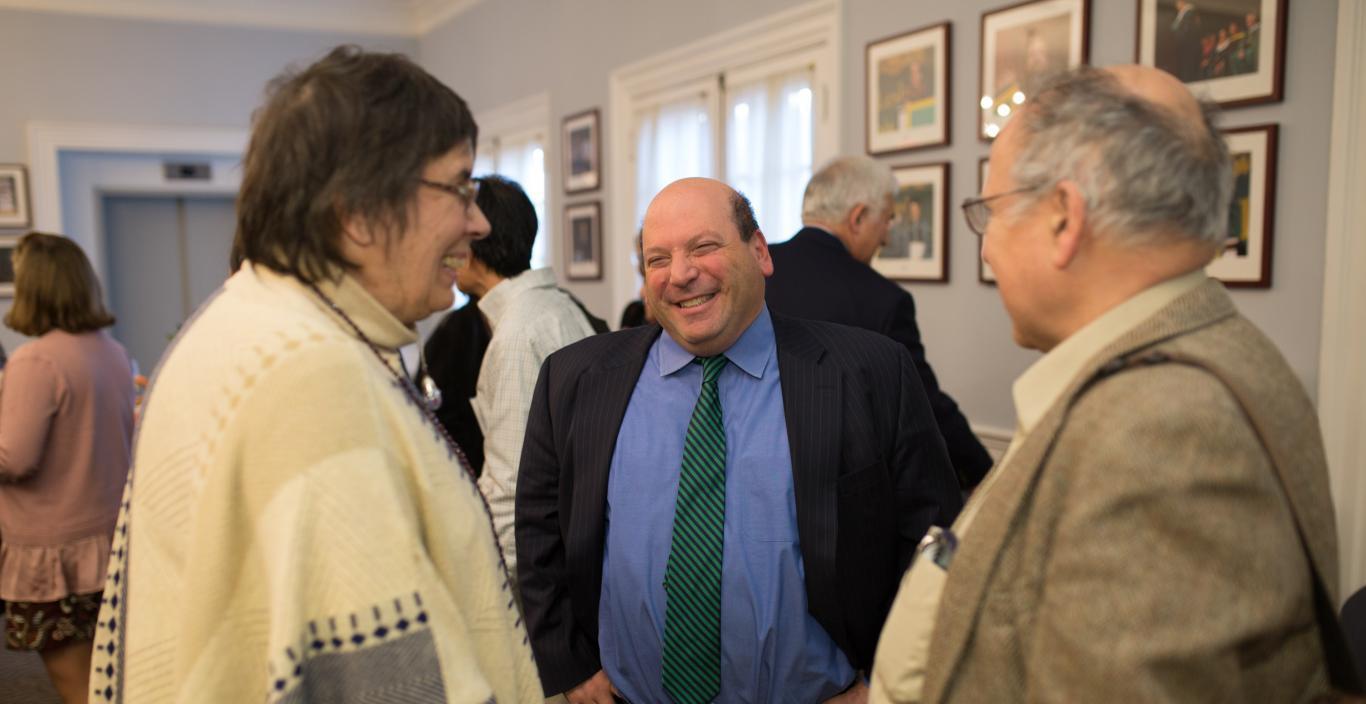 Jeff Weiss smiles while talking to two people in Alumni Hall.