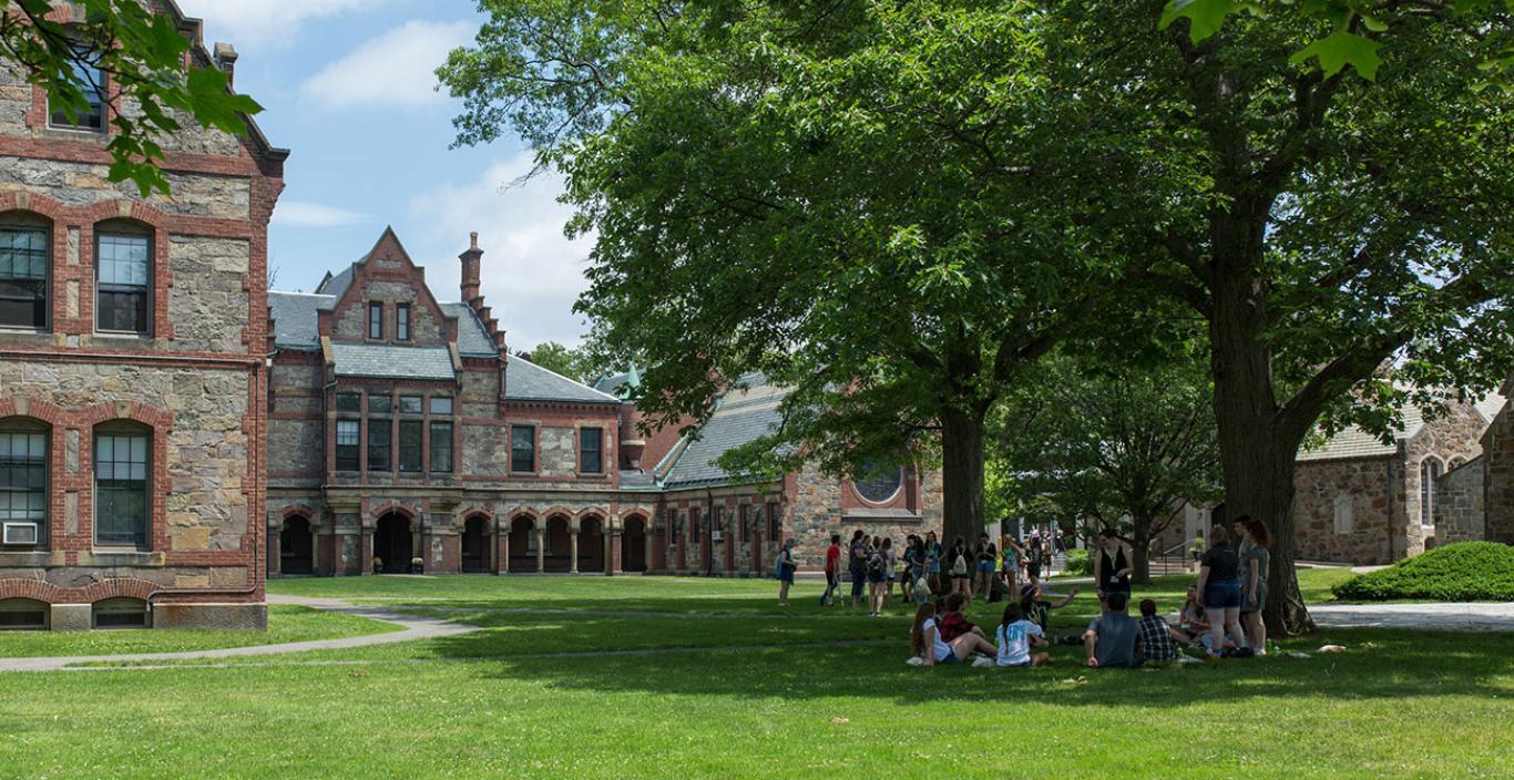 Two circles of students sitting on Lesley's lawn during new student orientation.