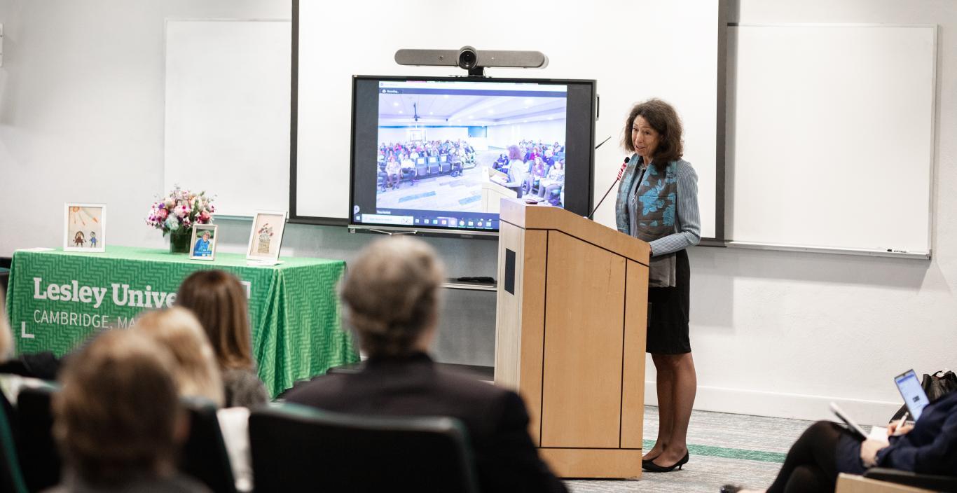Janet Steinmayer standing at podium in front of presentation screen.