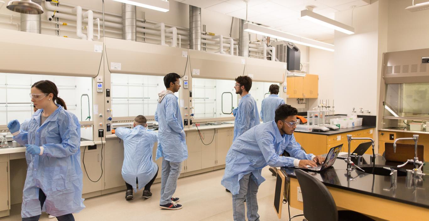 Landscape view of the lab with students working in their lab coats.