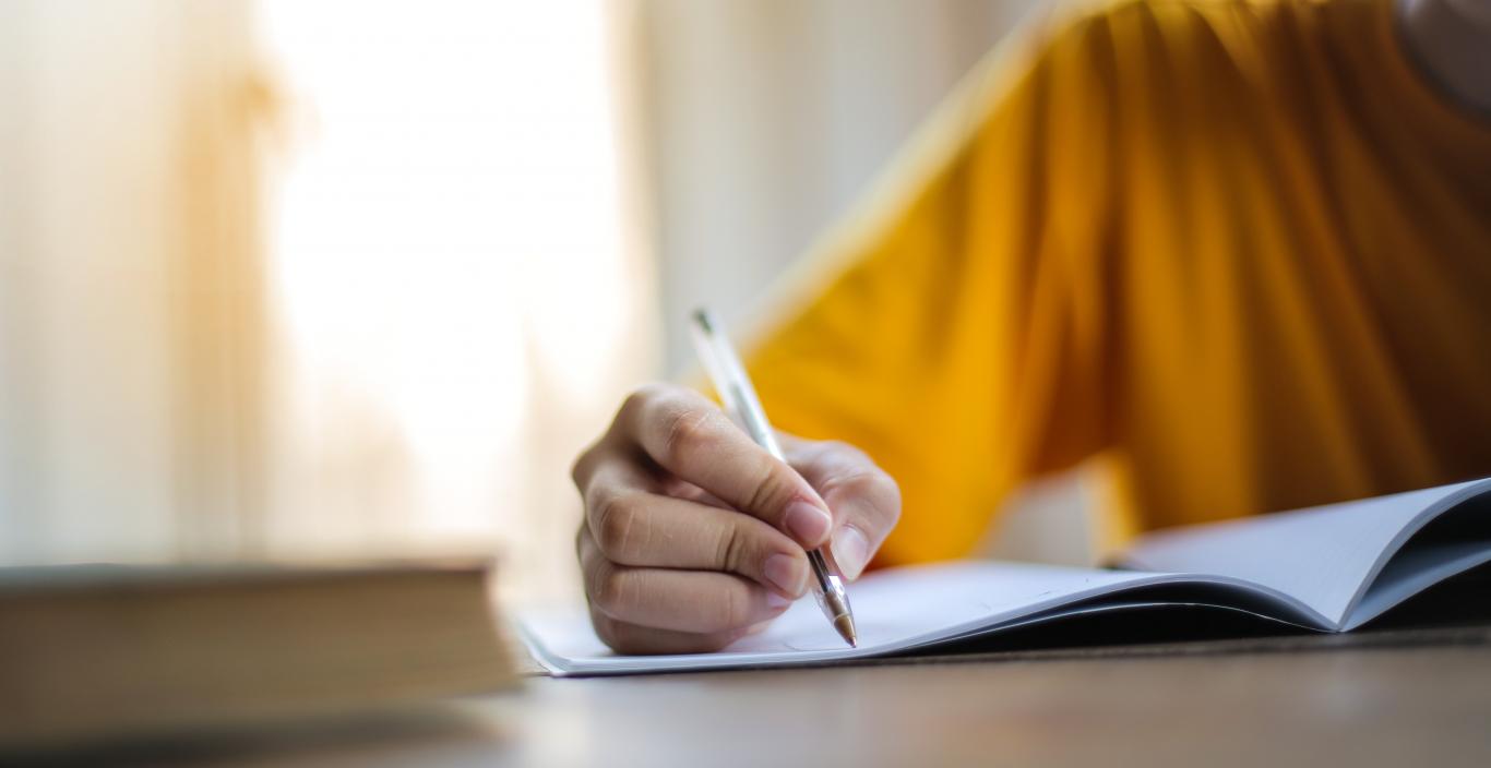 A person's hand on a desk, writing