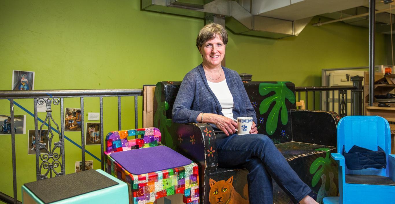 Woman sitting on a colorful chair in a classroom.