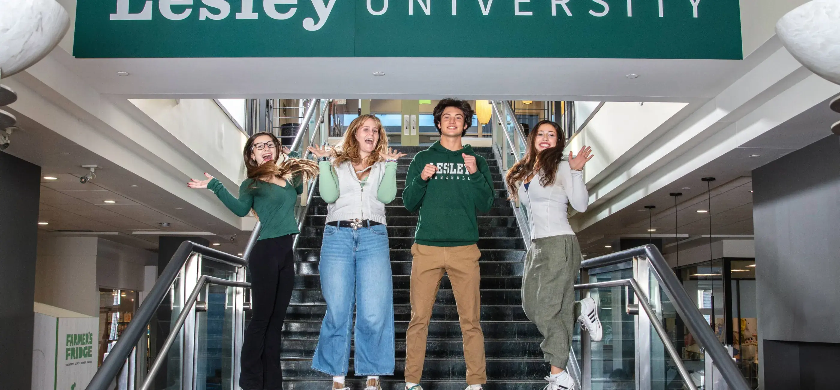 four Lesley students jump beneath a Lesley University banner