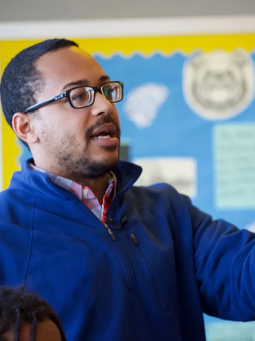 man in glasses talking in blue sweater
