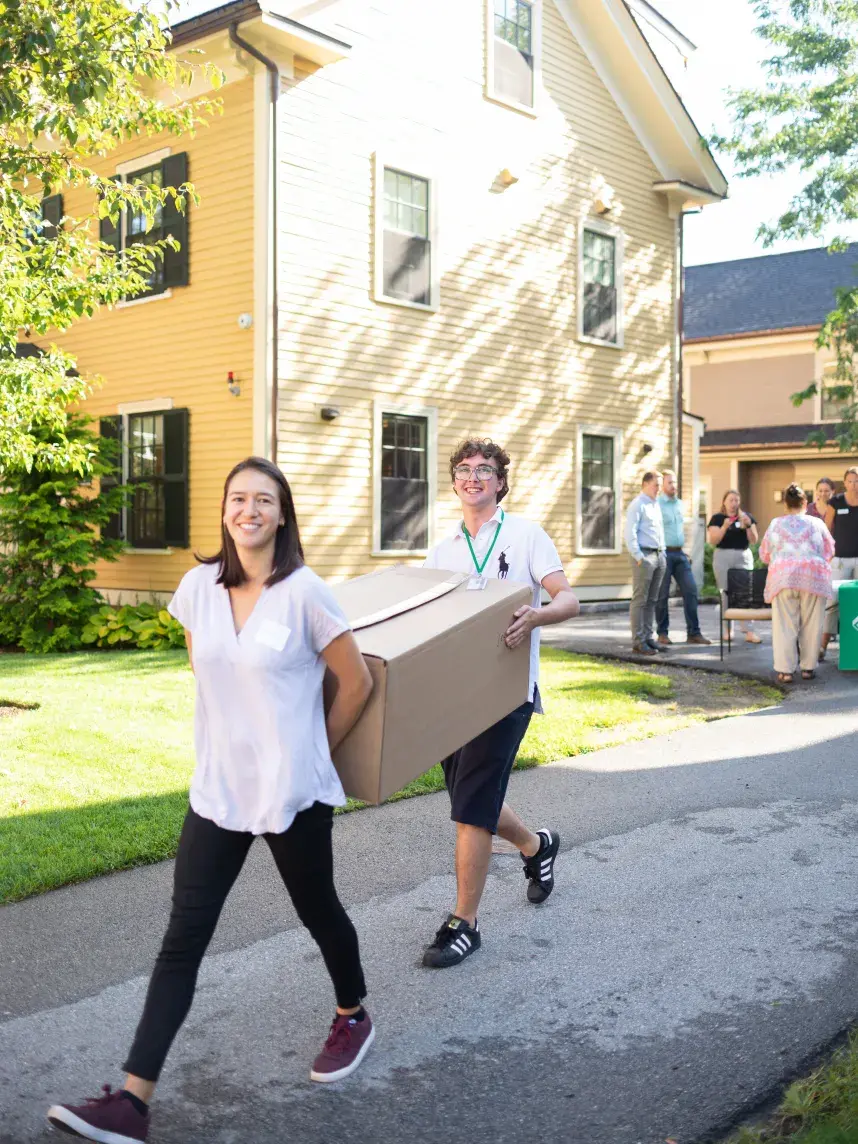 Students carrying large box down driveway