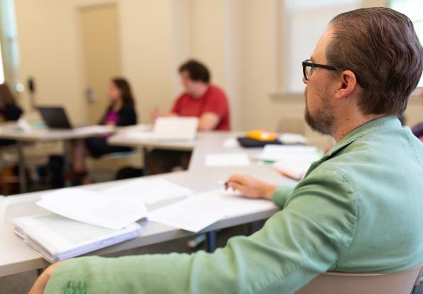 mfa creative writing boston Man sitting while listening and writing.