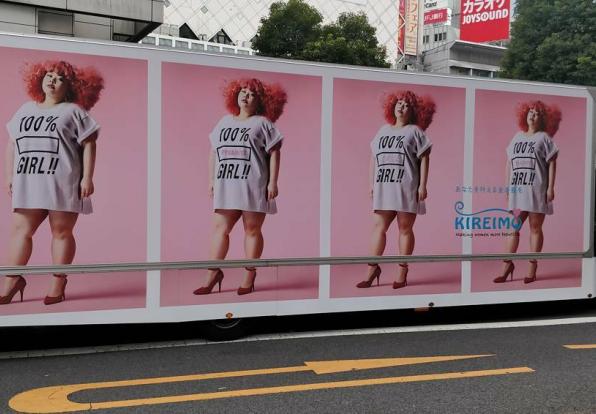 An advertisement on an 18-wheeler with a woman with red hair and a shirt that says 100% girl. Repeated four times on the truck.