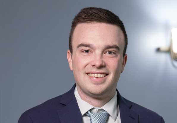 Headshot of Eric Pappas smiling with a blue-gray background