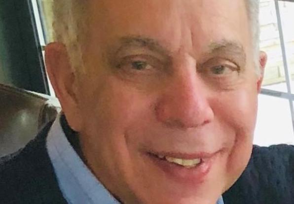 Photo of Glenn Mangurian smiling in front of a window