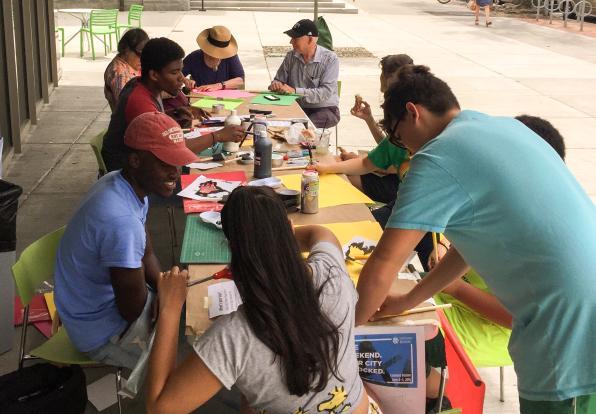 students sitting outside creating flags on the sidewalk