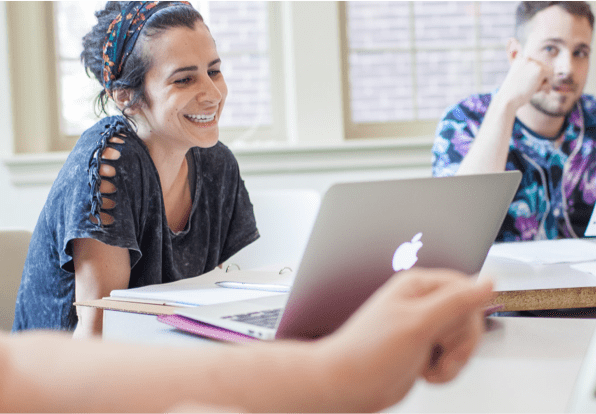 girl sitting at laptop smiling during class