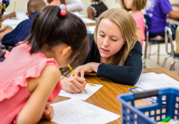 female teacher helping young students at desk
