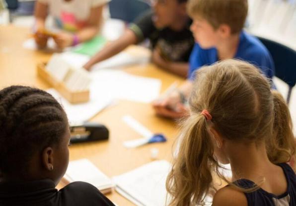 classroom students sit around the table doing schoolwork