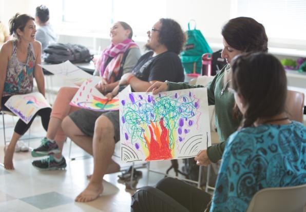students sitting in chairs holding up drawings