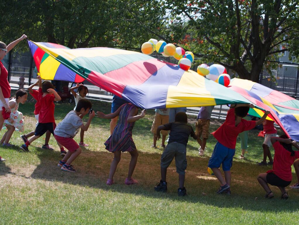Summer Compass children playing outside under colorful parachute