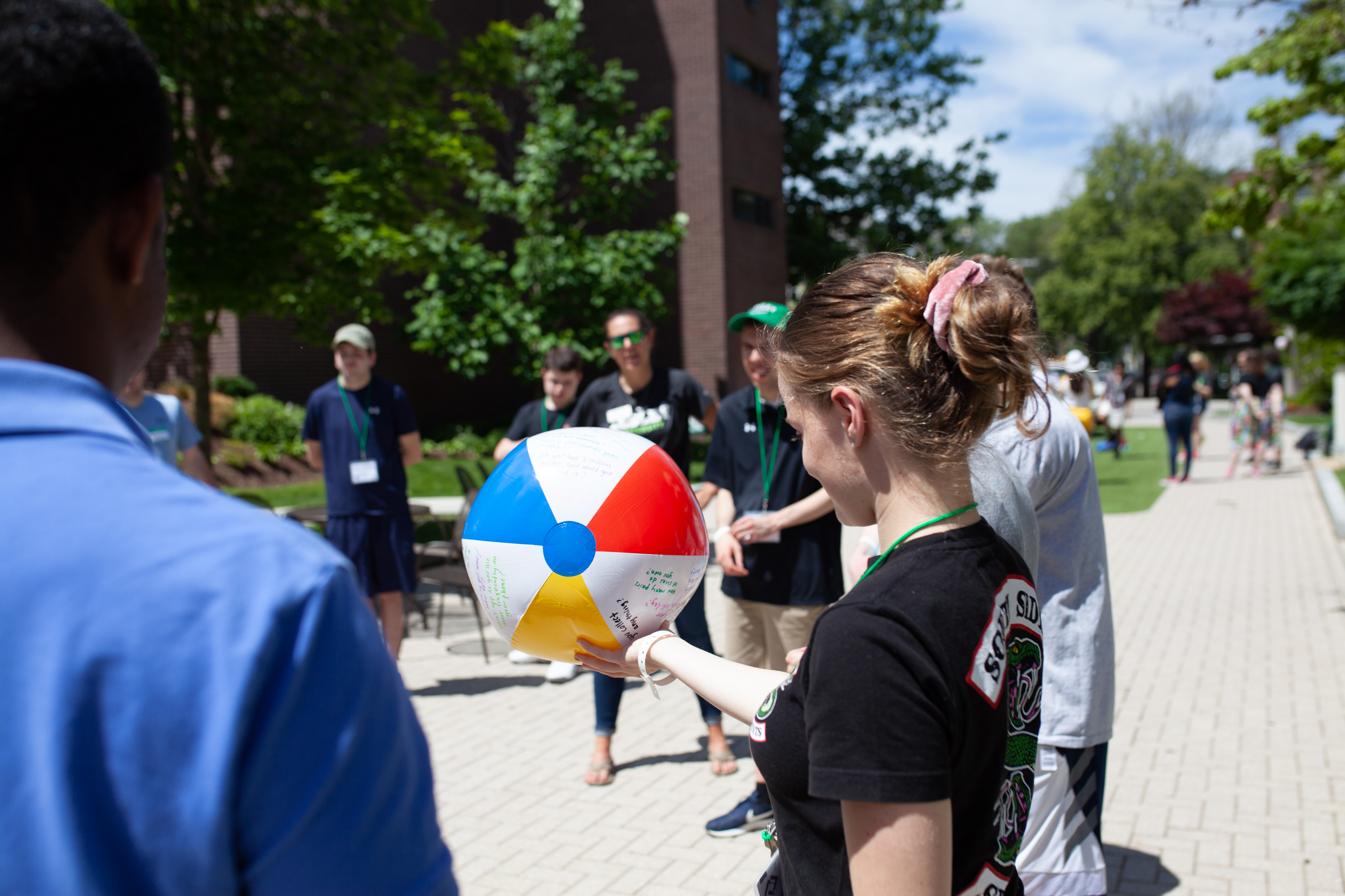 Student standing outside in a circle holding a beach ball on a sunny summer day